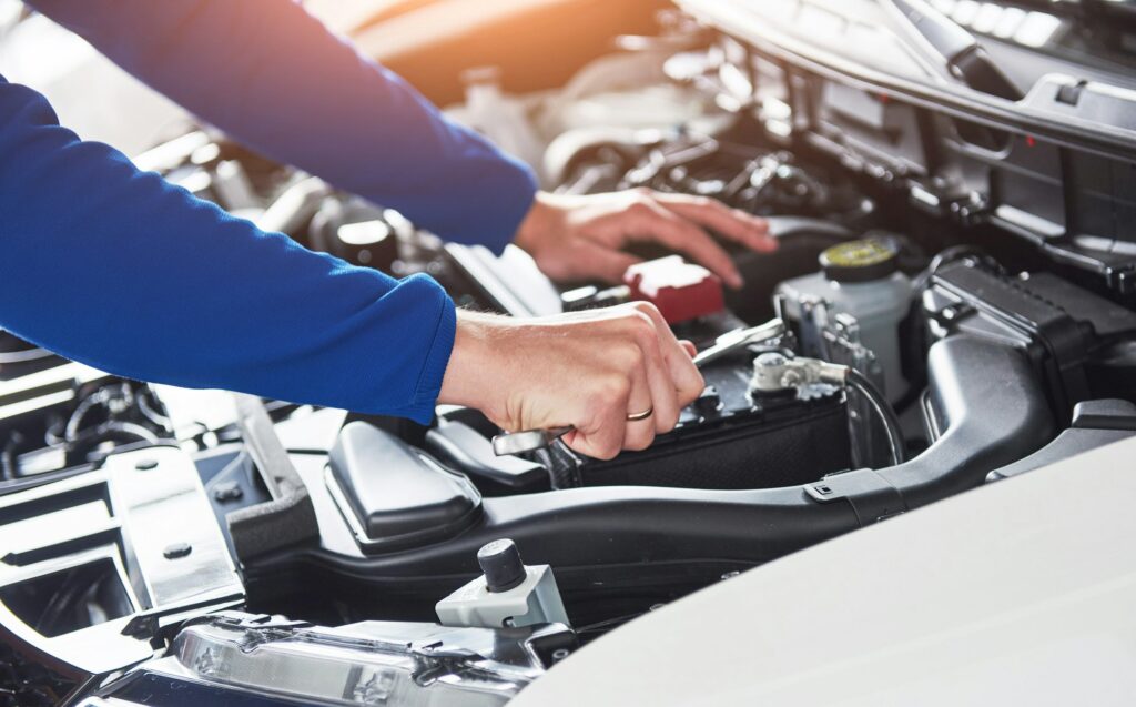 Hands of car mechanic with wrench in garage